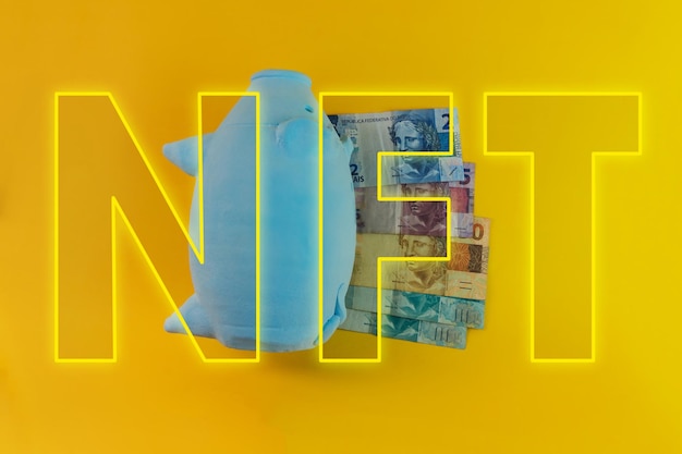 NFT written with piggy bank and Brazilian money isolated on yellow background NFT Finance image