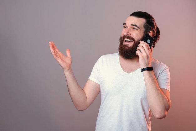 Nice bearded man is talking on the phone while gesturing in a studio