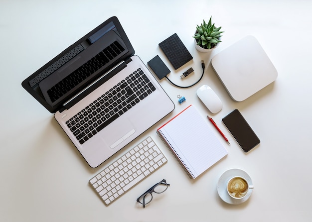 Nice and bright work desk with computer equipment and coffee, overhead view