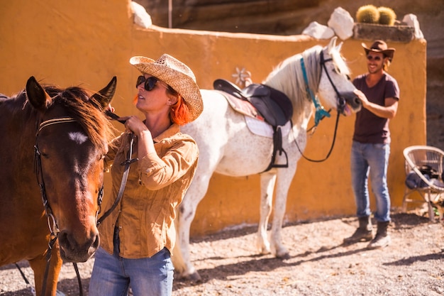 Nice caucasian couple outdoor prepare and check horse equipments ready to go live a new adventure travel in aloternative way to discover a natural paths and world country life concepts for young