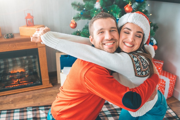 Nice and cheerful picture of young couple embrace each other. They smile. She keeps eyes closed. 