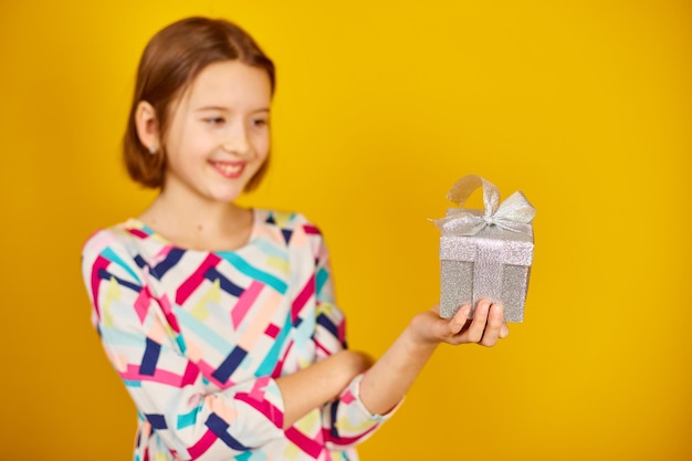 Nice child teenage girl hold silver present box in a hand in the studio