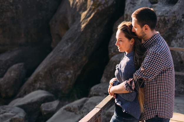 Nice couple hugging and enjoying a windy autumn day at rocks