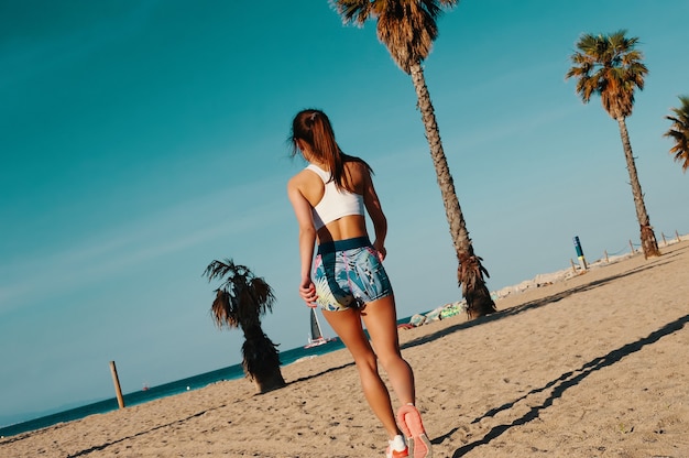 Nice day for training. Rear view of beautiful young woman in sports clothing jogging while exercising outdoors