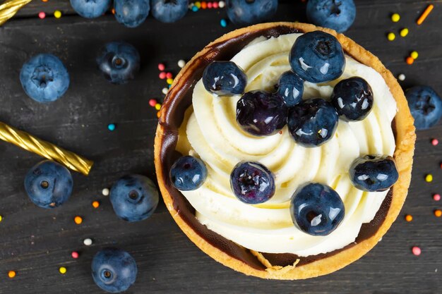 Nice food Small cake with cream and berries on a dark background