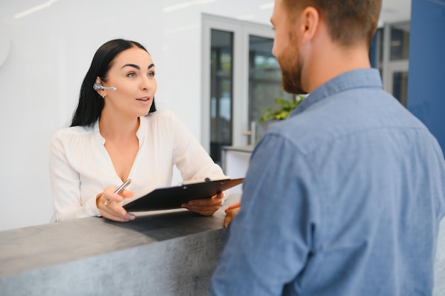 Nice friendly woman talking to the client while standing at the reception