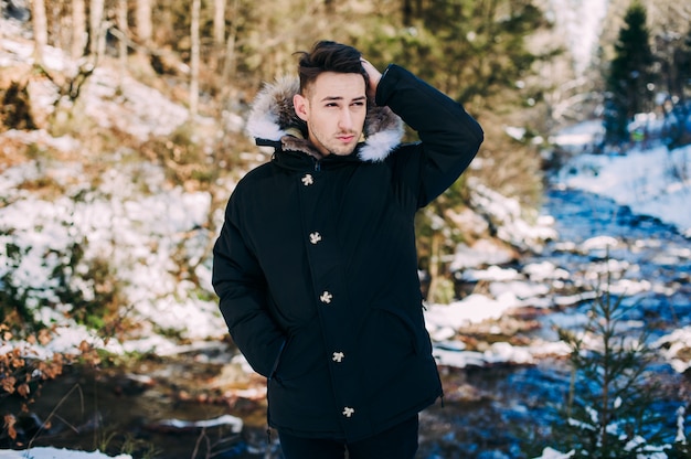 NICE guy model posing near the waterfall in winter mountains