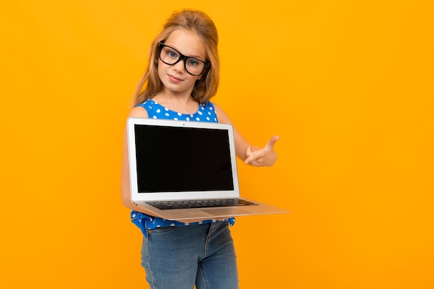 Nice little girl with glasses holds a laptop and smiles isolated