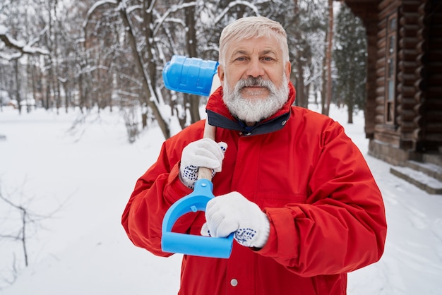 Nice man looking at camera while removing snow in wintertime