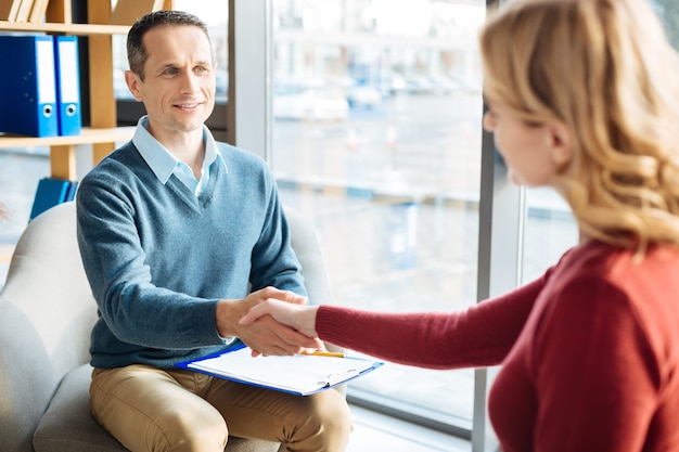 Nice to meet you. Joyful friendly nice man looking at his patient and smiling while greeting her