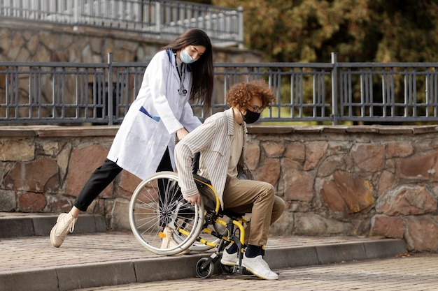 Nice nurse helps a patient in a wheelchair down the stairs Assistance to a disabled patient