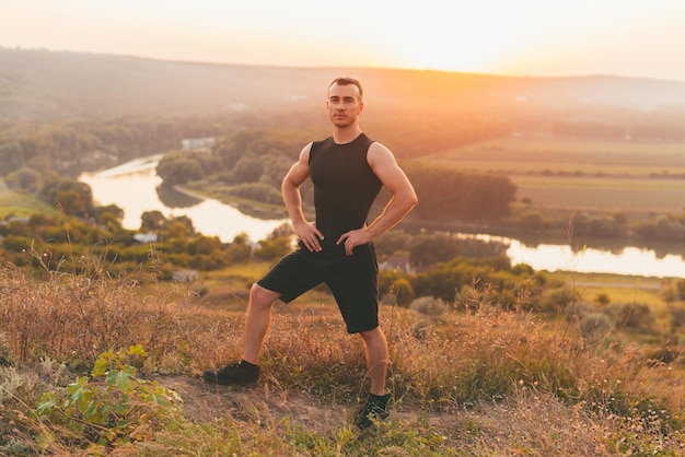 A nice photo of a man with muscles on a hill looking at the camera