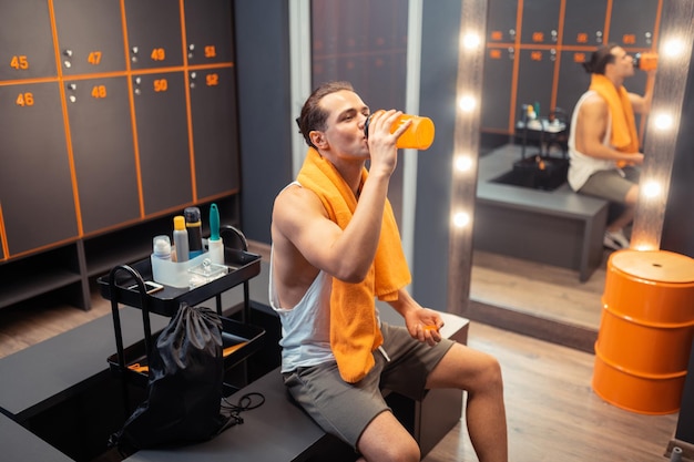 Nice positive man drinking fresh water from the bottle