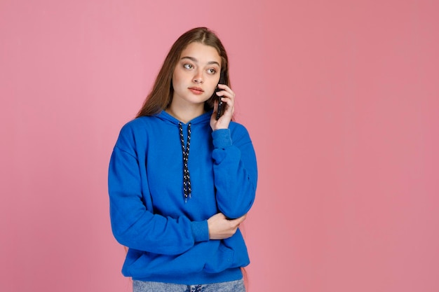 Nice serious female with pensive face talking on mobile phone while looking away indoors