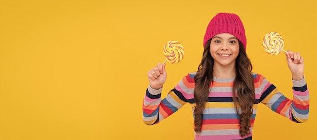 Nice smile hipster kid with colorful lollypop sugar candy on stick caramel candy shop Teenager child with sweets poster banner header copy space