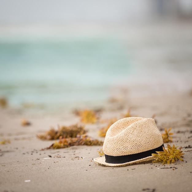 Nice straw hat laying on the sand Beautiful ocean beach background. Outdoors. Vacation time