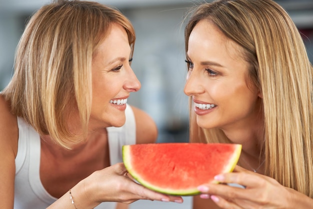 Nice two adult girls in the kitchen with watermelon