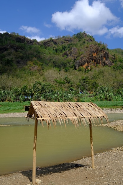 nice view on rocky river bank during dry season. bamboo hut by the river. limestone mountains. blue