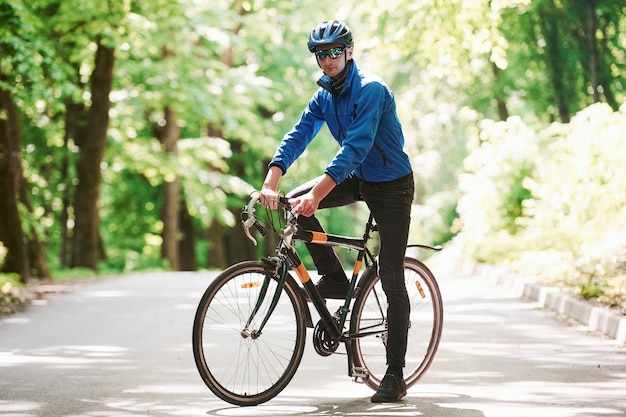 Nice weather today. Cyclist on a bike is on the asphalt road in the forest at sunny day