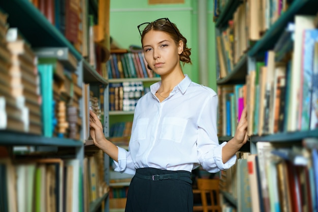 A nice woman in a white shirt in the library is smiling