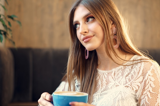 Nice young woman enjoying cup of coffee in a coffee shop