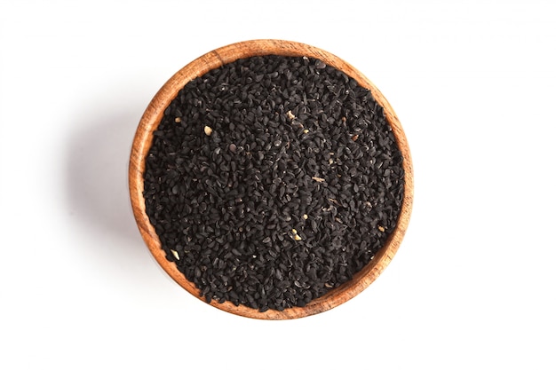 Nigella sativa or Black cumin in wooden bowl on white background, copy space, top view, isolate