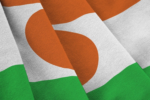 Niger flag with big folds waving close up under the studio light indoors The official symbols and colors in banner