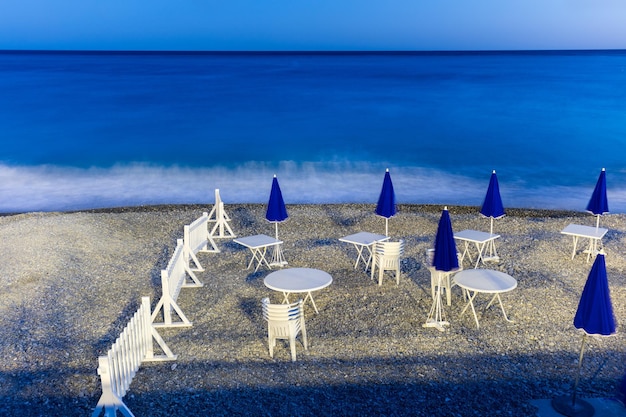 Night beach with parasols tables ans chairs