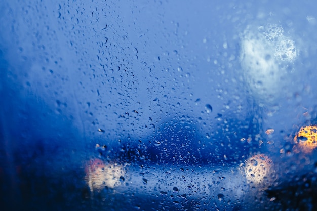 Night city lights through windshield abstract background water drop on the glass lights and rain.