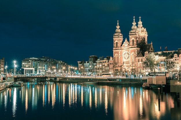 Night city view of Amsterdam canal and Basilica of Saint Nicholas, Holland, Netherlands. Long exposure.. Toning in cool tones