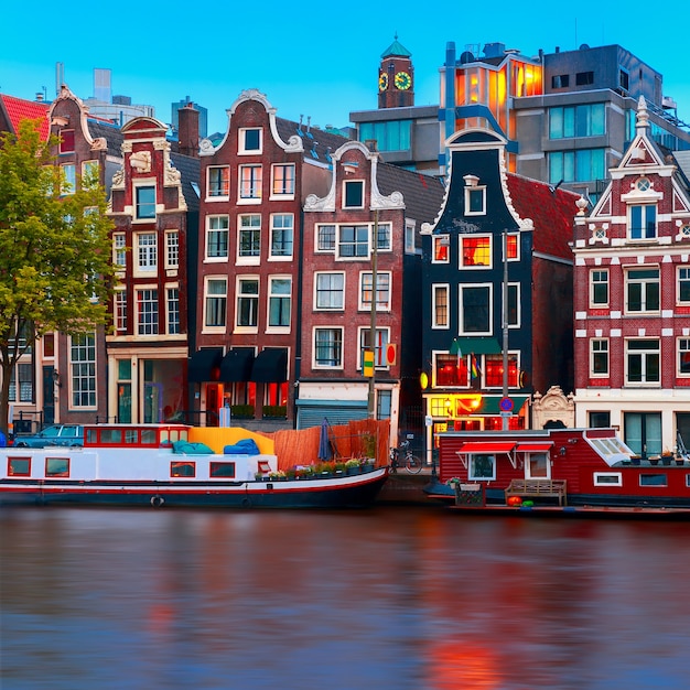 Night city view of Amsterdam canal, typical dutch houses and boats, Holland, Netherlands.