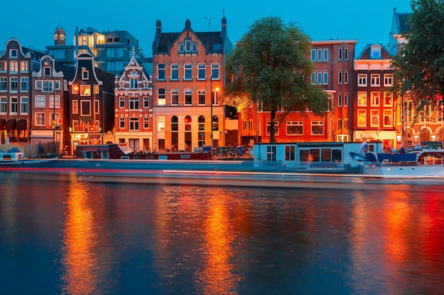 Night city view of Amsterdam canal, typical dutch houses and boats, Holland, Netherlands.