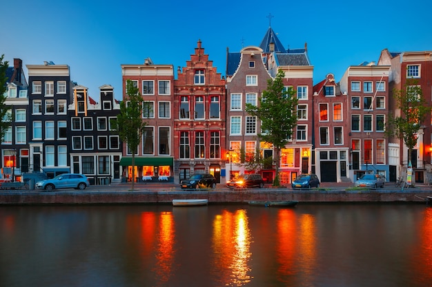 Night city view of Amsterdam canal, typical dutch houses and boats, Holland, Netherlands.