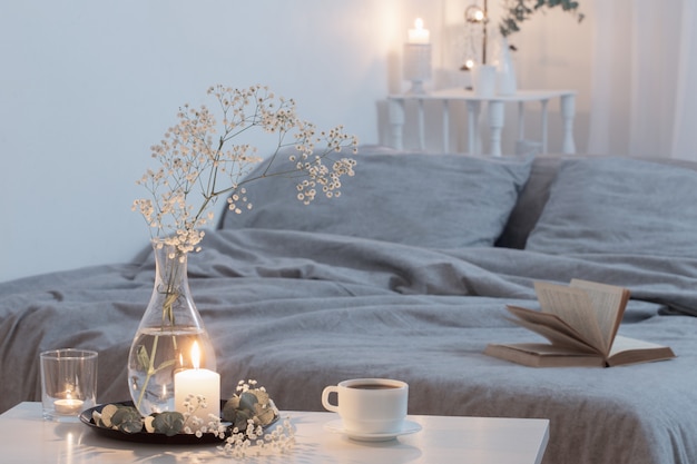 Night interior of bedroom with flowers and burning candles