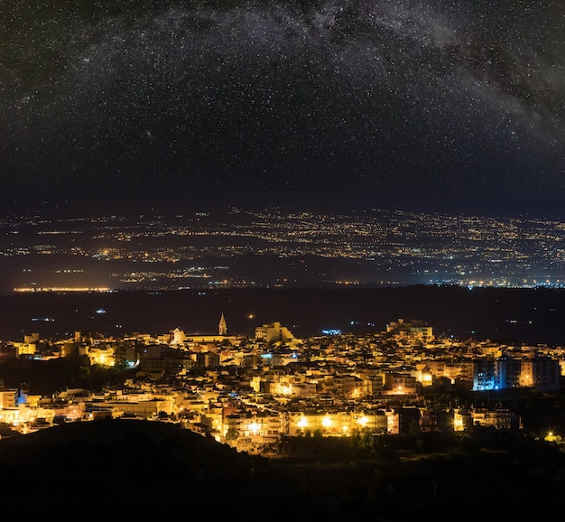 Night Lentini town view in direction from mountain road to sea and Etna volcano Siracusa Sicily Italy and Milky Way stars above