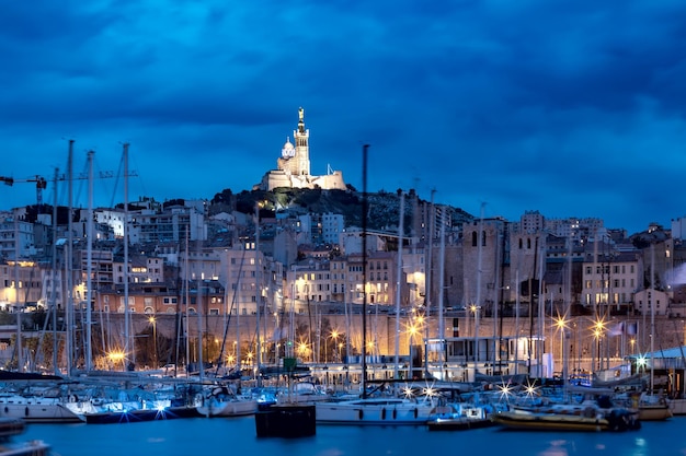 Night old port and the basilica of notre dame de la garde on the background on the hill marseille fr