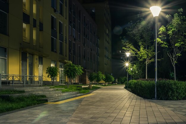 Night park paths and colored houses at summer night Night paths benches and lanterns