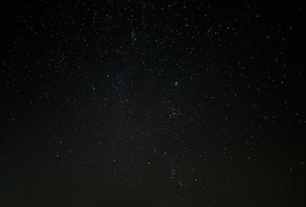 The night starry sky, a dark outer space with nebulae and constellations.