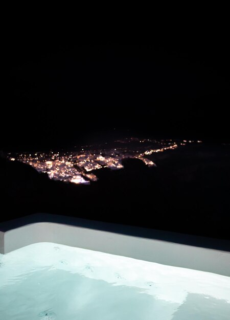 Photo night view of fira, from a private pool in imerovigli, santorini