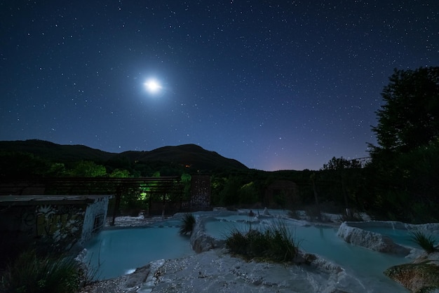 Night view geothermal pool and hot spring in Tuscany Italy Bagni San Filippo natural thermal waterfall in the evening by moon light and stars in the sky