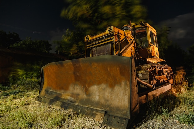 Nightshot long exposure shot of old abandoned yellow tractor in nature