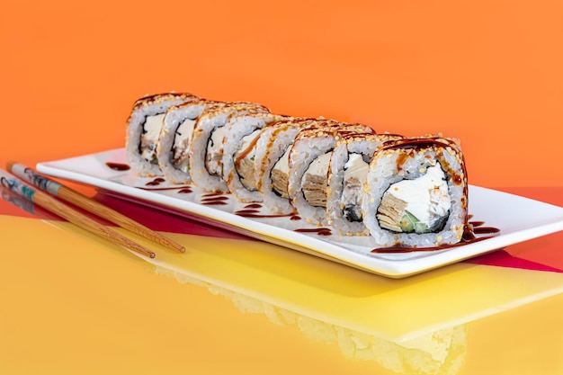 Nigiri sushi sets Uramaki California Philadelphia on a white plate Near ginger and wasabi Soy sauce in a white bowl On a colored background