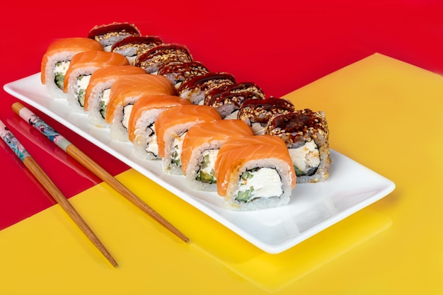 Nigiri sushi sets Uramaki California Philadelphia on a white plate Near ginger and wasabi Soy sauce in a white bowl On a colored background