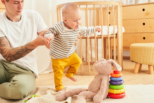 A ninemonthold baby takes steps with the support of his father's hands