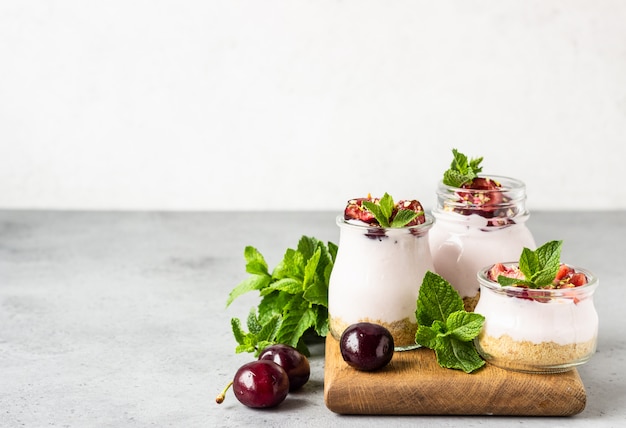 No baked cheesecake with cherry in glass jars, fresh cherries and mint. Healthy dessert. 