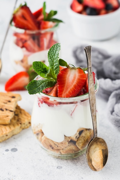 Photo no baked dessert treifl or cheesecake with strawberries in sliced jars on an old concrete surface