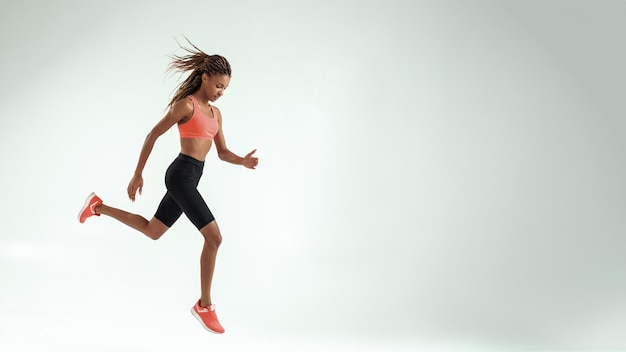 No limits full length of young african woman with perfect body in sports clothing jumping