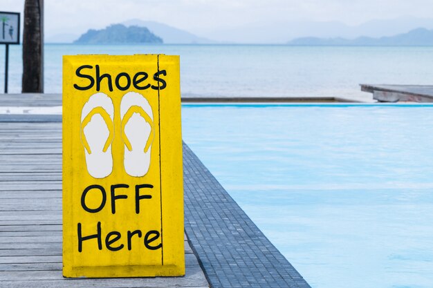 No shoes sign by the swimming pool on the wooden floor in yellow color