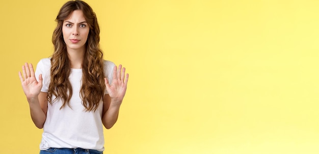 Photo no thats enough seriouslooking confident woman restrain man demand stay away give refusal look intense prohibit rejecting suspicious unpleasant offer stand yellow background