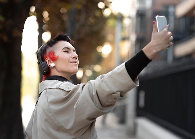 Non binary person with modern hairstyle taking a selfie